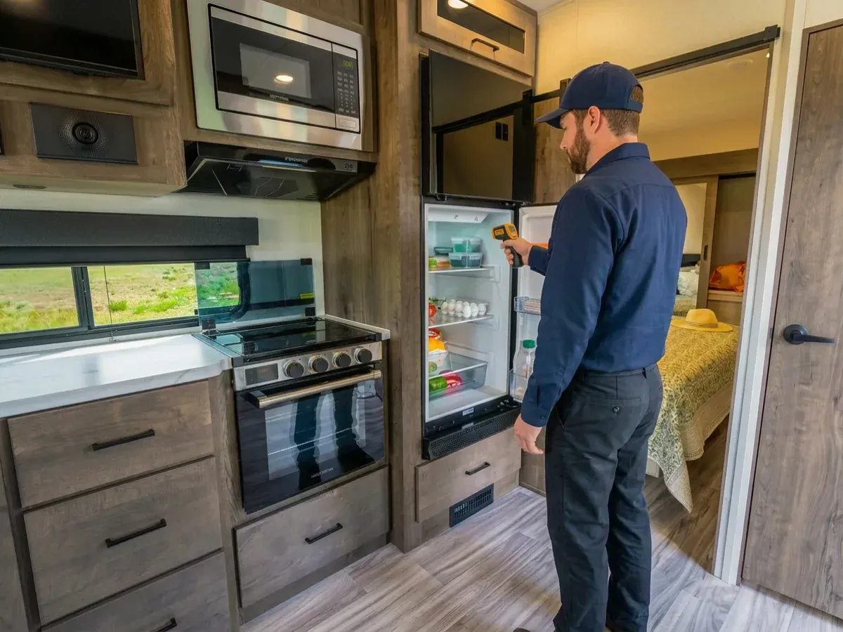 Mobile RV technician using an infrared thermometer to check an RV refrigerator in Georgetown Texas