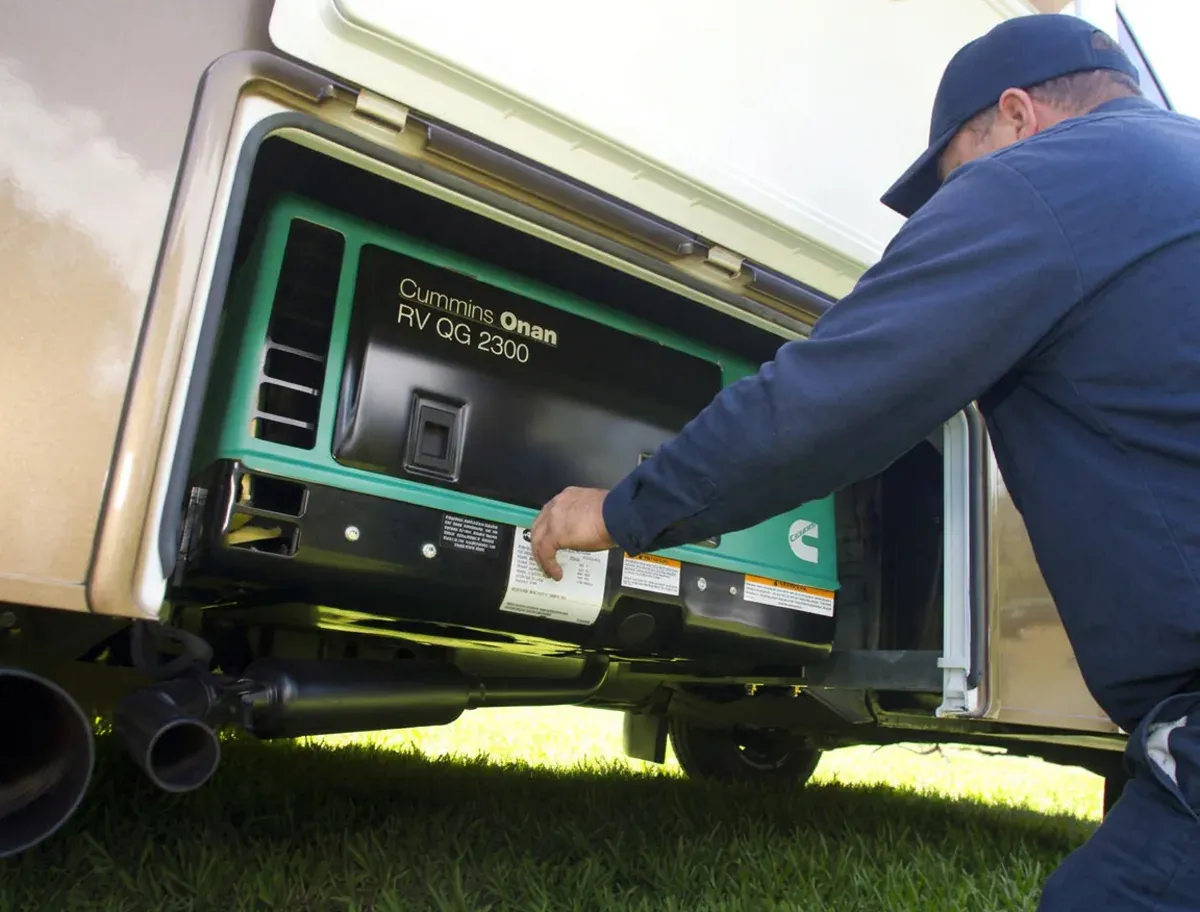 RV technician reaching into an open generator compartment to service a Cummins Onan generator in Georgetown Texas